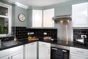 a kitchen with white cabinets and a clock on the wall at The Old Brewery Boardroom - Winchester City Centre, Free Parking for 2 Cars, Sleeps 6 in Winchester