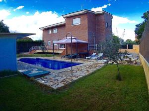 un patio trasero con piscina y una casa en Villa Pilara en Brunete