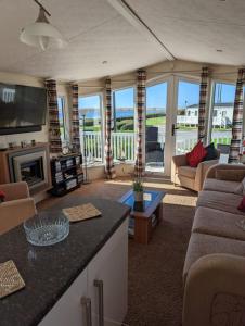 a living room with a couch and a table at Lovely and Bright Caravan Haven Littlesea with views across the Fleet Lagoon in Weymouth