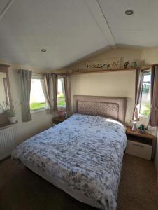 a bedroom with a bed in a room with windows at Lovely and Bright Caravan Haven Littlesea with views across the Fleet Lagoon in Weymouth