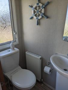 a bathroom with a white toilet and a sink at Lovely and Bright Caravan Haven Littlesea with views across the Fleet Lagoon in Weymouth