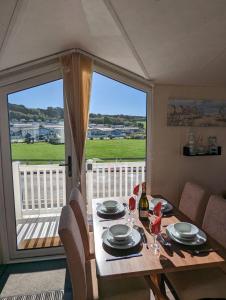 a dining room table with a view of a large window at Lovely and Bright Caravan Haven Littlesea with views across the Fleet Lagoon in Weymouth