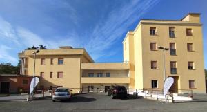 un grand bâtiment avec des voitures garées dans un parking dans l'établissement Apulia Hotel Roma, à Rome