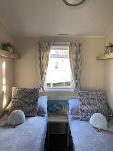 Habitación pequeña con 2 camas y ventana en Seton Sands Holiday Park Klover Karavans, en Port Seton