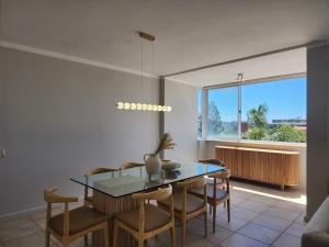 a dining room with a table and chairs and a window at Sandy Lodge 201 in Cape Town