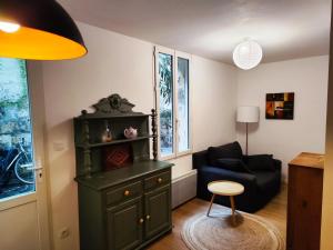 a living room with a green cabinet and a chair at Charming apartment downtown Bordeaux in Bordeaux