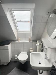 een badkamer met een toilet, een wastafel en een raam bij Haus Sommerwind; Wohnung 3 in Sankt Peter-Ording