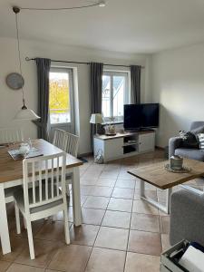 een woonkamer met een tafel en een televisie bij Haus Sommerwind; Wohnung 3 in Sankt Peter-Ording