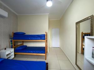 a room with three bunk beds and a mirror at Casa aconchegante próximo ao SESC Bertioga/SP. in Bertioga
