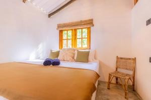 平谷Coconut Cabin - Hiriketiya Beach的窗户和椅子的房间里的一个床位