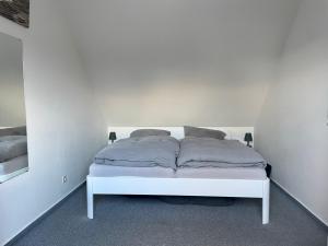 een wit bed met 2 kussens in een kamer bij Haus Sommerwind; Wohnung 3 in Sankt Peter-Ording