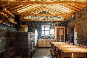 a dining room with a wooden table and chairs at Adega do Fogo in São Roque do Pico