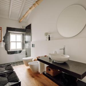 a bathroom with two toilets and a sink and a mirror at Adega do Fogo in São Roque do Pico