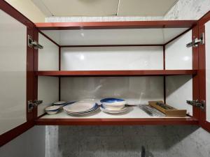 a cabinet with plates and bowls on a shelf at Furnished Studio Apartment in Abu Dhabi