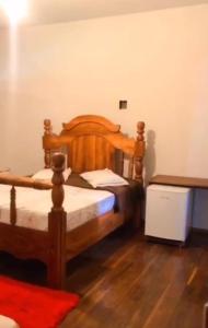HOTEL FAZENDA CANARIO DA TERRA في Rio Novo: غرفة نوم بسرير خشبي وارضية خشبية