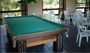 a pool table in a room with white chairs at HOTEL FAZENDA CANARIO DA TERRA in Rio Novo
