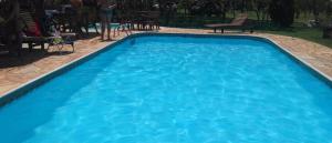 a swimming pool with blue water in a yard at HOTEL FAZENDA CANARIO DA TERRA in Rio Novo