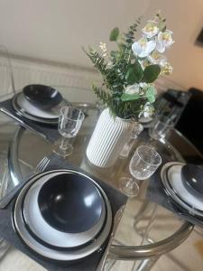 einen Glastisch mit Platten und eine Vase mit Blumen in der Unterkunft The Drake Apartment in Plymouth