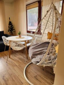 a hammock in a living room with a table at HAFCIK Apartamenty przyjazne dzieciom in Poronin