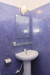 Baño de azulejos azules con lavabo y espejo en Chimaca Bay Hotel, en Arugam Bay