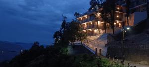 een gebouw op een heuvel 's nachts met lichten bij Hotel Wild Spring Mussoorie in Mussoorie