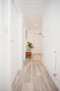 a hallway with white walls and an orange chair at Stylish 2 Bedroom Apt - Parking - 5 Mins walk to Beach in Bournemouth