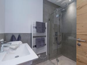 een badkamer met een douche, een wastafel en een glazen douchecabine bij Penning.Tirol in Hopfgarten im Brixental