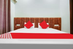 a red and white bed with red pillows on it at OYO Flagship Dhruva Residency in Shāhpur