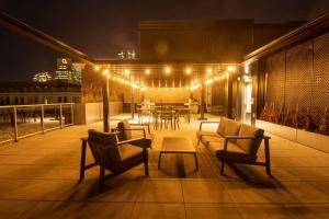 a rooftop patio with chairs and a table with lights at Bel Appartement au centre-ville Montréal in Montreal