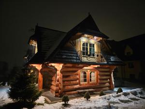 a log cabin with lights on it in the snow at Domek Góralski Amelka in Poronin