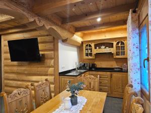 a kitchen with wooden walls and a table with a television at Domek Góralski Amelka in Poronin