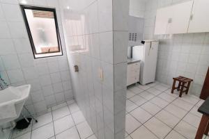eine Küche mit weiß gefliesten Wänden und einem Kühlschrank in der Unterkunft Residencial Chanel in Balneário Camboriú