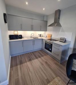 a kitchen with white cabinets and a wooden floor at The Cove Apartment, Portstewart near Prom, Parking in Portstewart