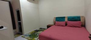 a bedroom with a bed with pink sheets and pink pillows at Homestay Kaklong in Kuala Terengganu
