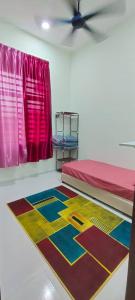 a room with a bed and a colorful rug on the floor at Homestay Kaklong in Kuala Terengganu