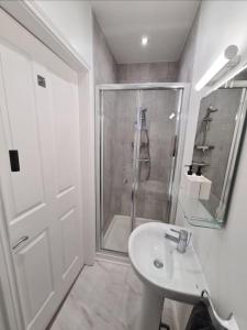 ein weißes Bad mit einer Dusche und einem Waschbecken in der Unterkunft The Cove Apartment, Portstewart near Prom, Parking in Portstewart