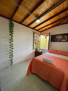 een slaapkamer met een bed met een oranje sprei bij Xplora Hostel in Caldas