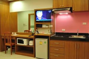 Il comprend une cuisine avec un évier et une télévision murale. dans l'établissement Green Harbor Hotel & Service Apartment, à Patong Beach