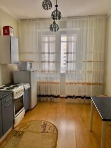 a kitchen with a stove and a window with curtains at 452 Возле Байтерека для компании 1-6 человек с 2 кроватями и диваном in Astana