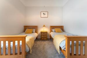 a bedroom with two beds and a night stand at Argaty Cottage in Doune