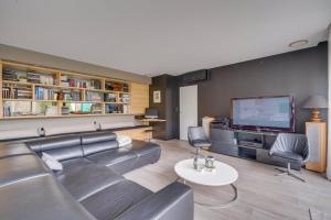 uma sala de estar com um sofá e uma televisão de ecrã plano em Spacious Bordeaux family home with swimming pool em Bordeaux
