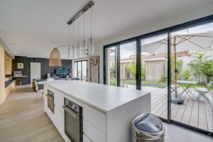 uma cozinha com um balcão branco e janelas grandes em Spacious Bordeaux family home with swimming pool em Bordeaux