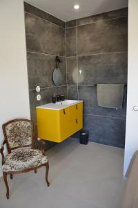 uma casa de banho com um lavatório amarelo e uma cadeira. em L'Arche de Noé em Aubenas