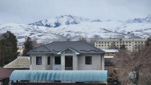 una casa frente a una montaña cubierta de nieve en Karakol Yurt Lodge & Homestay, en Karakol