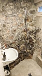 uma casa de banho em pedra com um lavatório e um chuveiro em Charmant mazot rénové em Fully