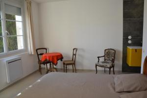 ein Schlafzimmer mit Stühlen, einem Bett und einem Tisch in der Unterkunft L'Arche de Noé in Aubenas