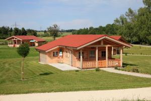 a large wooden house with a red roof at Alpenchalets Hotel Lambach in Seebruck