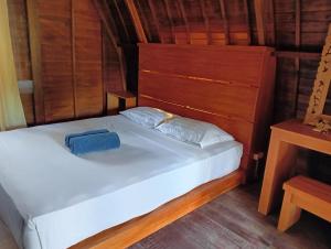 a bedroom with a white bed with a wooden headboard at Villa Lumbung Petanahan in Jembrana