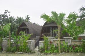 a house with palm trees in front of it at Villa Lumbung Petanahan in Jembrana