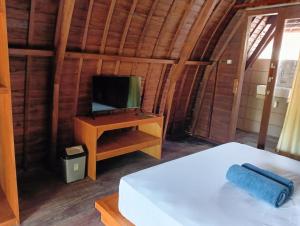 a bedroom with a bed and a tv on a desk at Villa Lumbung Petanahan in Jembrana